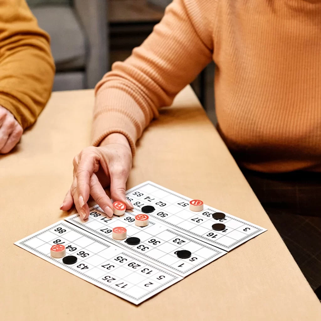 A person with a bingo card and chips on a table, placing a chip on the card.